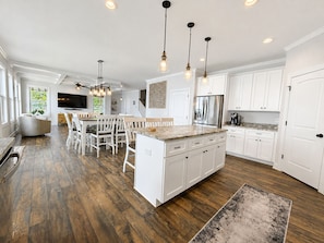 A spacious kitchen with white cabinetry, a central island, and a dining area with white chairs. - MAIN-LAKE VIEWS Boat Slip + Community Pool-Golf Cart-Sleeps 12 (Littleton)