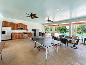 A spacious indoor area with a ping pong table, kitchen area, ceiling fans, and a view of a swimming pool. - MAIN-LAKE VIEWS Boat Slip + Community Pool-Golf Cart-Sleeps 12 (Littleton)