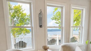 A room with two armchairs, a small wooden side table, and a view of the sea through large windows. - MAIN-LAKE VIEWS Boat Slip + Community Pool-Golf Cart-Sleeps 12 (Littleton)