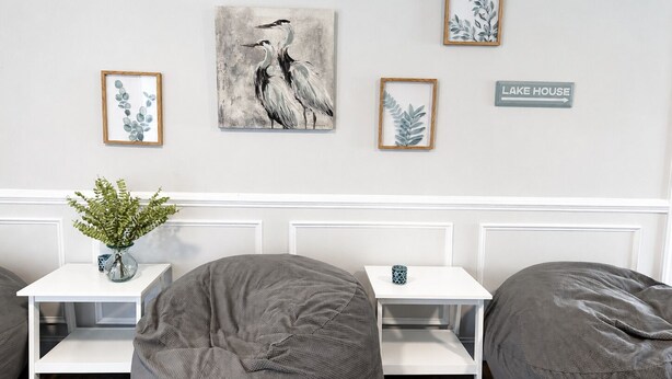 A room with a white wall, a bench, two bean bags, and framed artwork. - MAIN-LAKE VIEWS Boat Slip + Community Pool-Golf Cart-Sleeps 12 (Littleton)