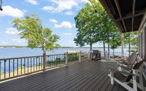 A wooden deck with a grill and chairs overlooking a lake. - MAIN-LAKE VIEWS Boat Slip + Community Pool-Golf Cart-Sleeps 12 (Littleton)