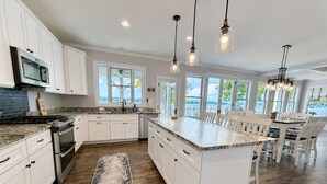A spacious kitchen with white cabinetry, a large island, and pendant lighting. - MAIN-LAKE VIEWS Boat Slip + Community Pool-Golf Cart-Sleeps 12 (Littleton)