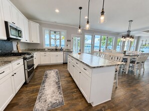 A spacious kitchen with white cabinetry, a large island, and pendant lighting. - MAIN-LAKE VIEWS Boat Slip + Community Pool-Golf Cart-Sleeps 12 (Littleton)