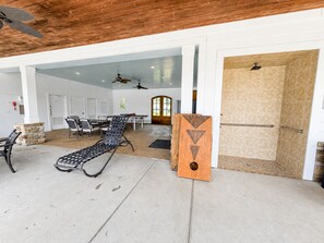 A spacious indoor area with a pool table, lounge chairs, and a door leading to a bathroom.