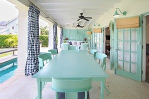 A covered outdoor dining area with a pool, light blue furniture, and a ceiling fan. - Cowrie Cottage | Private Pool | Near Gibbes Beach (Gibbes)