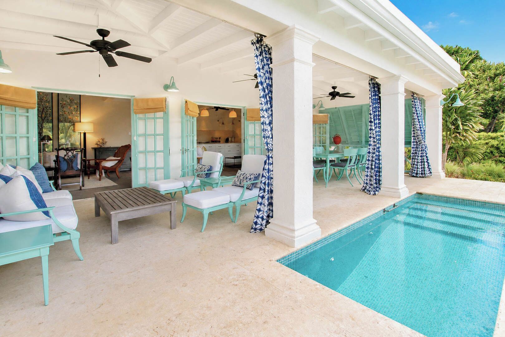 Un espacio al aire libre techado con piscina, asientos y vistas al interior.