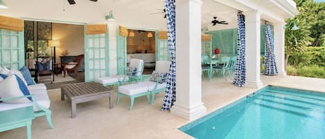 Un espacio al aire libre techado con piscina, asientos y vistas al interior.