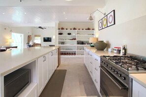A modern kitchen with white cabinetry, a gas stove, and a central island. - Cowrie Cottage | Private Pool | Near Gibbes Beach (Gibbes)