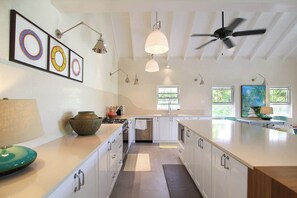 A modern kitchen with white cabinetry, a central island, pendant lighting, and a ceiling fan. - Cowrie Cottage | Private Pool | Near Gibbes Beach (Gibbes)