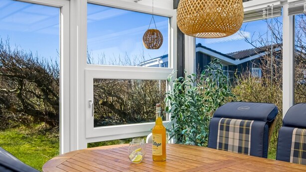 An outdoor seating area with a table, chairs, and a bottle of alcohol. - "Ingalil" - 200m from the sea by Interhome (Løkken)