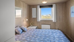 A bedroom with a bed, a bedside table, a mirror, a window, and a wall-mounted heater. - "Ingalil" - 200m from the sea by Interhome (Løkken)