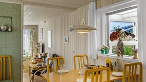 A dining area with a wooden table and chairs, a hanging light fixture, and a window with a view. - "Ingalil" - 200m from the sea by Interhome (Løkken)