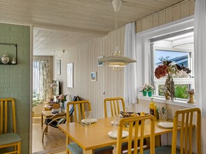 A dining area with a wooden table and chairs, a hanging light fixture, and a window with a view. - "Ingalil" - 200m from the sea by Interhome (Løkken)