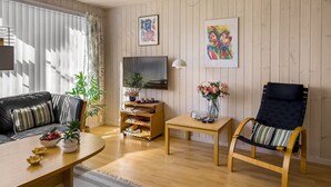 A living room with a sofa, a TV, a coffee table, a chair, and a small table with a vase of flowers. - "Ingalil" - 200m from the sea by Interhome (Løkken)