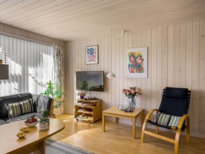 A living room with a sofa, a TV, a coffee table, a chair, and a small table with a vase of flowers. - "Ingalil" - 200m from the sea by Interhome (Løkken)