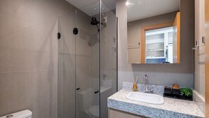 A modern bathroom with a glass-enclosed shower, a white sink, and a mirror above the countertop. - Studio in Cond. W/pool 480m the Lighthouse Spb0407 (Salvador)