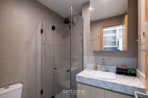 A modern bathroom with a glass-enclosed shower, a white sink, and a mirror above the countertop. - Studio in Cond. W/pool 480m the Lighthouse Spb0407 (Salvador)