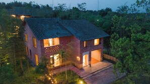 Une maison à deux étages, dotée d’un toit en pente et entourée d’une végétation luxuriante.