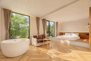 Une chambre moderne avec une grande baignoire, un canapé et un lit.