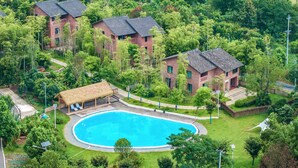 A residential area with a swimming pool surrounded by lush greenery and traditional brick buildings. - Haiyang Village Wildwood Resort Wuhan (Wuhan)