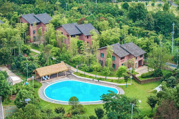 A residential area with a swimming pool surrounded by lush greenery and traditional brick buildings.