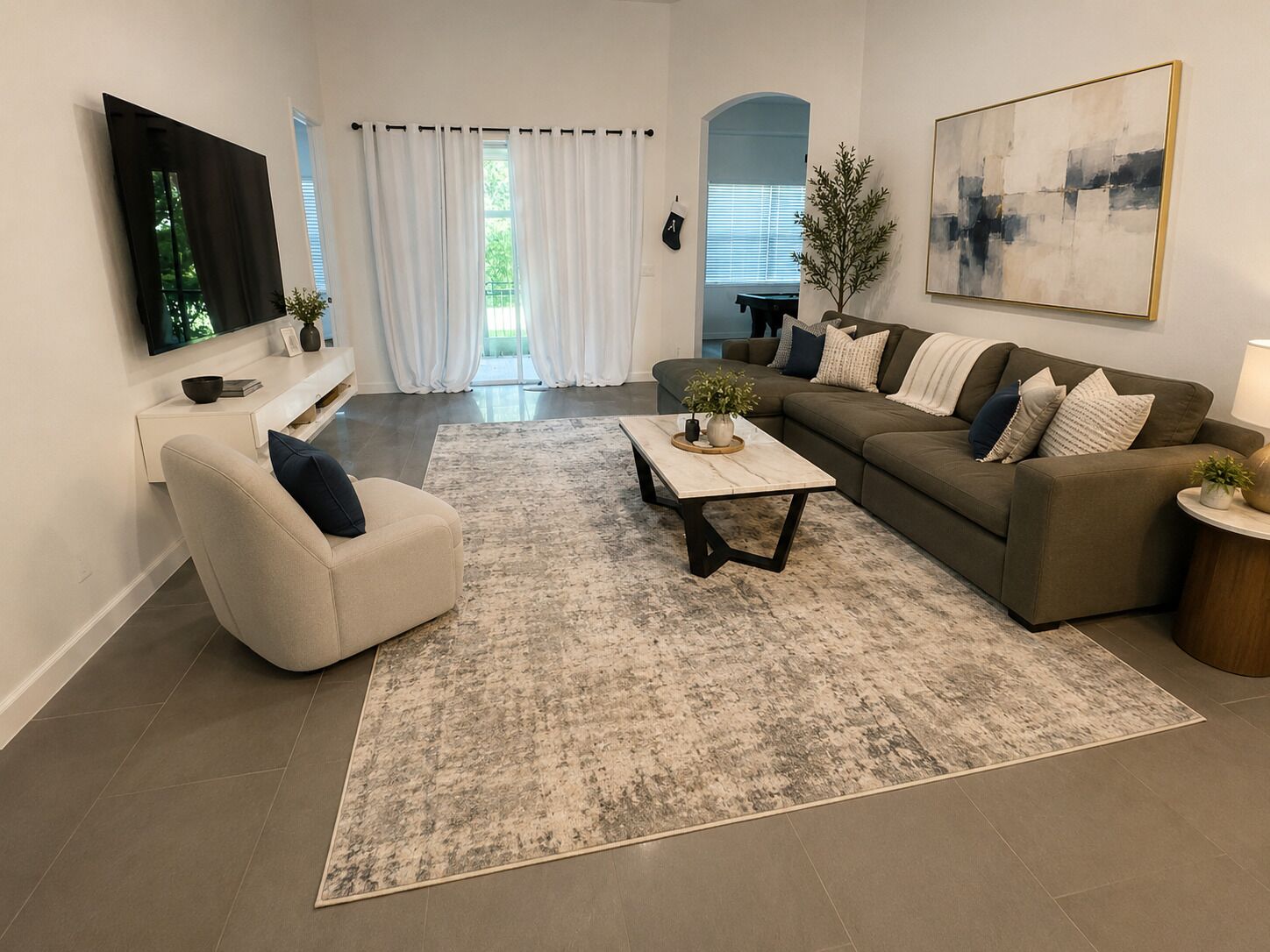 A modern living room with a sofa, armchair, coffee table, and a painting on the wall.