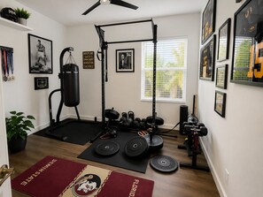 A home gym with a punching bag, weight plates, and a squat rack. - Spectacular four bedroom built-in gym, built-in game room, in gorgeous Naples (Naples)