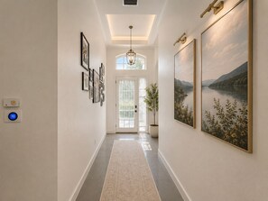 A hallway with a large painting, a potted plant, and a thermostat. - Spectacular four bedroom built-in gym, built-in game room, in gorgeous Naples (Naples)