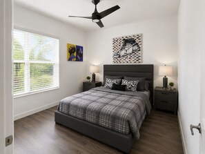 A bedroom with a bed, two bedside tables, a ceiling fan, and artwork on the walls. - Spectacular four bedroom built-in gym, built-in game room, in gorgeous Naples (Naples)