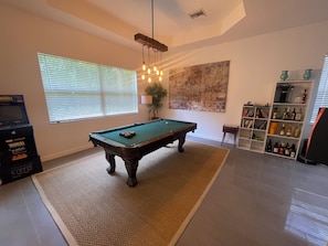 A pool table in a room with a bookshelf and a painting on the wall. - Spectacular four bedroom built-in gym, built-in game room, in gorgeous Naples (Naples)
