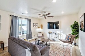 A living room with a sofa, coffee table, and a TV mounted on the wall. - Luxury Kanab Hot Tub - Trails & Pets OK (Kanab)