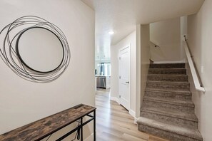 Eine Treppe, die zu einer zweiten Etage führt, eine hölzerne Bank und ein rundes Objekt an der Wand.