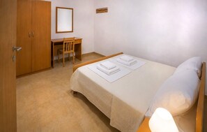 Ein Schlafzimmer mit einem Bett, einem Schreibtisch und einem Sessel.