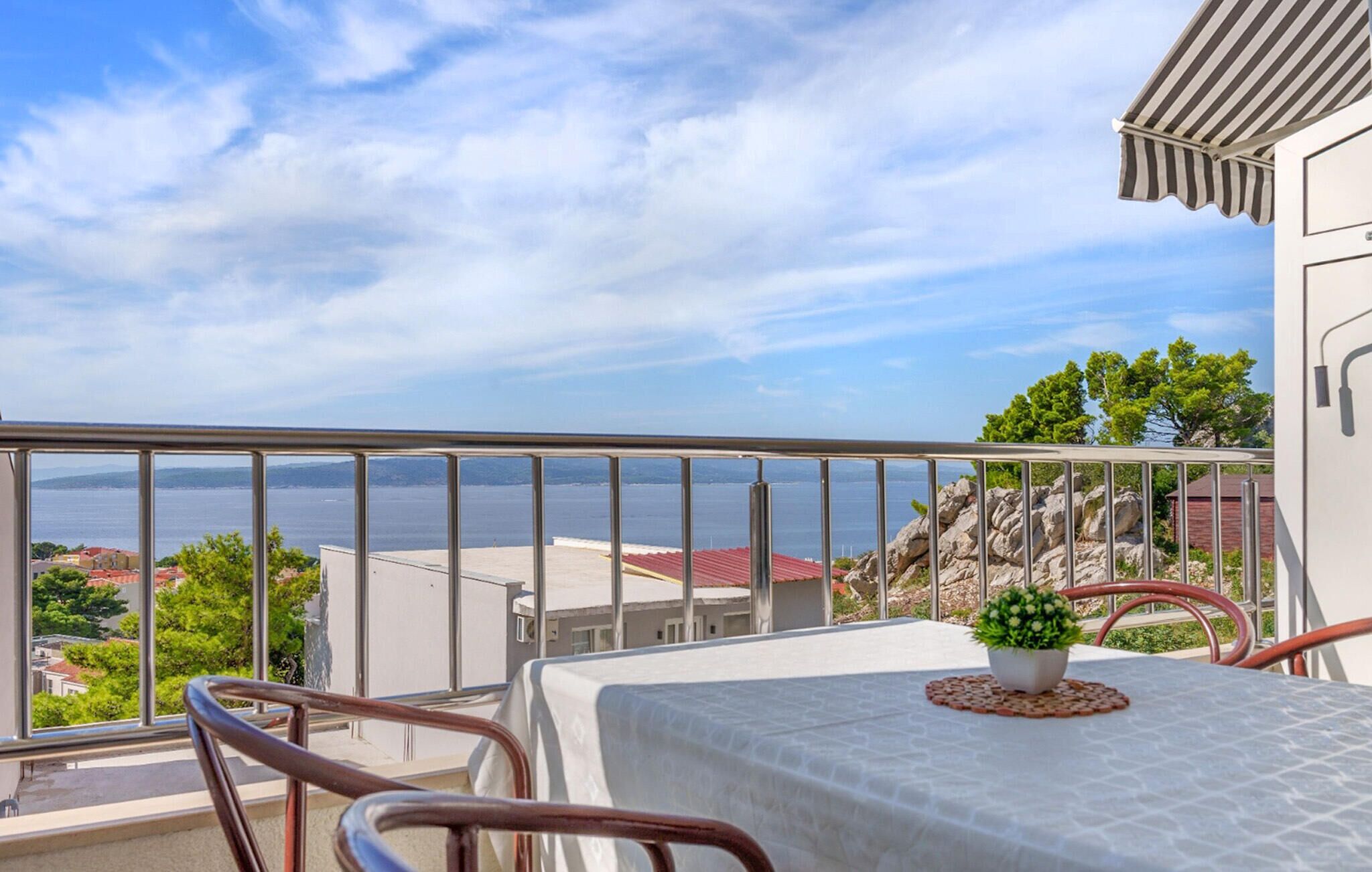 A balcony with a metal railing, a table with a white tablecloth, and a potted plant.