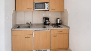 Eine kompakte Küche mit einer Mikrowelle, einer Kaffeemaschine und einem Wasserkocher auf der Arbeitsfläche.