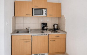 Eine kompakte Küche mit einer Mikrowelle, einer Kaffeemaschine und einem Wasserkocher auf der Arbeitsfläche.