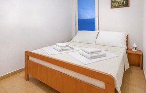 A single-bed room with a wooden frame, white bedding, a small bedside table with a lamp, and a window with blue blinds. - Gorgeous apartment in Baska Voda (Baska Voda)