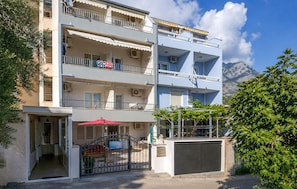 A multi-story building with balconies, a gated entrance, and a mountain view in the background. - Gorgeous apartment in Baska Voda (Baska Voda)