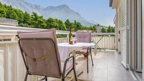 Uma varanda com mesa e cadeiras, uma garrafa de vinho e vista para as montanhas.