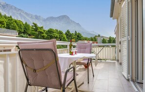 Ein Balkon mit Tisch und Stühlen, einer Weinflasche und Bergblick.