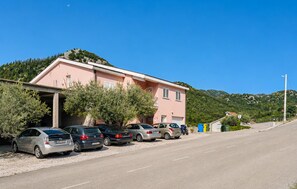 Ein pinkfarbenes Gebäude mit überdachtem Parkplatz und parkenden Autos davor.