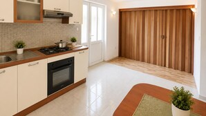 A modern kitchen with a stove, oven, and cabinets. There is a window and a wooden door. - 6 bedroom pet friendly apartment in Vrgorac (Vrgorac)