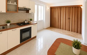 A modern kitchen with a stove, oven, and cabinets. There is a window and a wooden door. - 6 bedroom pet friendly apartment in Vrgorac (Vrgorac)