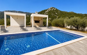 A swimming pool with lounge chairs and a pergola structure, surrounded by greenery and mountains. - 6 bedroom pet friendly apartment in Vrgorac (Vrgorac)
