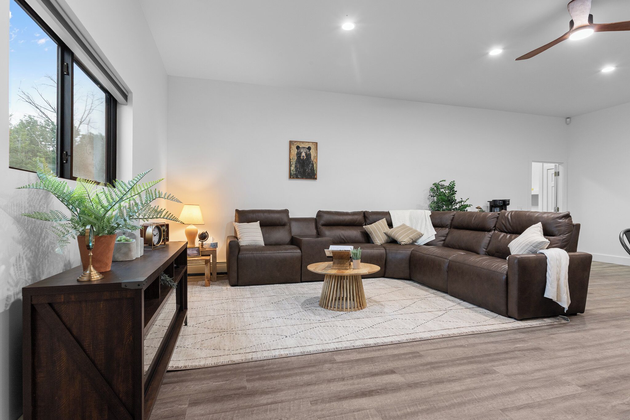 Un salon moderne avec un canapé d’angle, une table basse et une plante en pot.