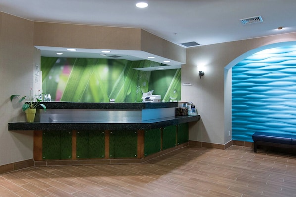 A reception area with a green and blue wall design, a reception desk, and a bench.
