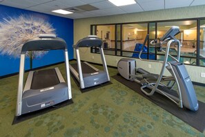A fitness room with treadmills and a stationary bike, carpeted floor, and a large window with a view of a pool. - Spacious Stays Made for Work & Weekend Getaways l Heated Pool (Greensboro)