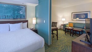 A hotel room with a bed, a desk, a chair, a sofa, and a painting on the wall. - Indoor Pool & Free Breakfast | Your Gateway to Greensboro's Best Experiences (Greensboro)