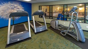 A fitness room with treadmills and a stationary bike, carpeted floor, and a large window with a view of a pool. - Indoor Pool & Free Breakfast | Your Gateway to Greensboro's Best Experiences (Greensboro)