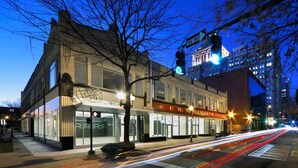 A historic building with a prominent corner entrance, a visible street sign, and a traffic light. - Stretch Out and Settle In Near Greensboro Hotspots l Heated Pool & Breakfast (Greensboro)